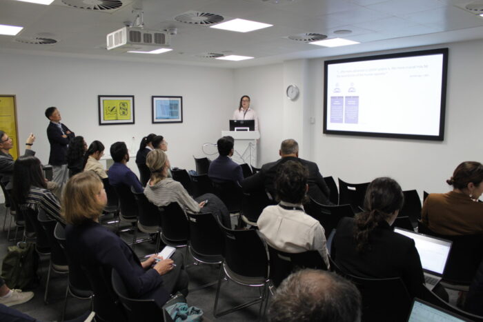 Dr Rafael Goncalves presents from a lecturn infront of a busy room of devegates