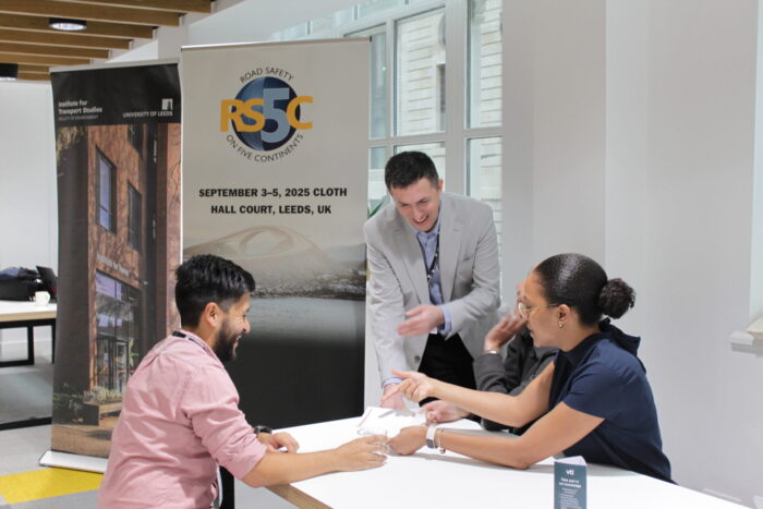 A delegate is welcomed to the conference by members of the University of Leeds team