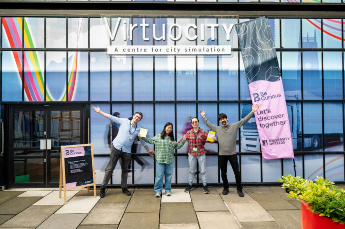 4 Members of the Virtuocity team outside the Virtuocity building with Be Curious banners