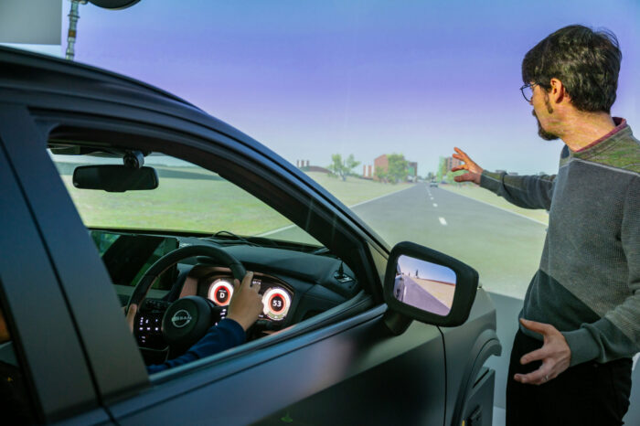 a child driving a simulator vehicle being instructed by a member of the Virtuocity team